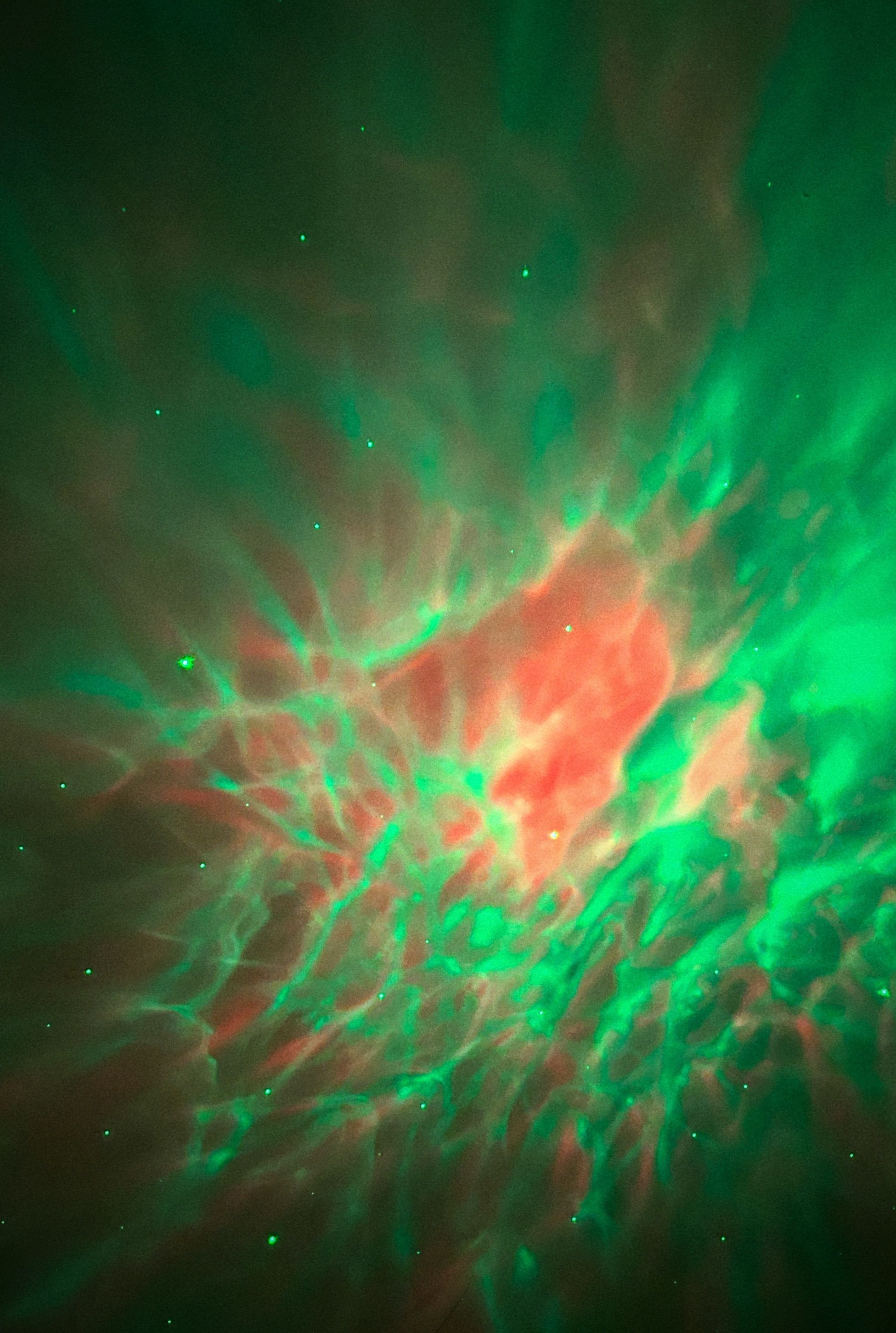 Dazzling nebula with swirling green and red colors in deep space.