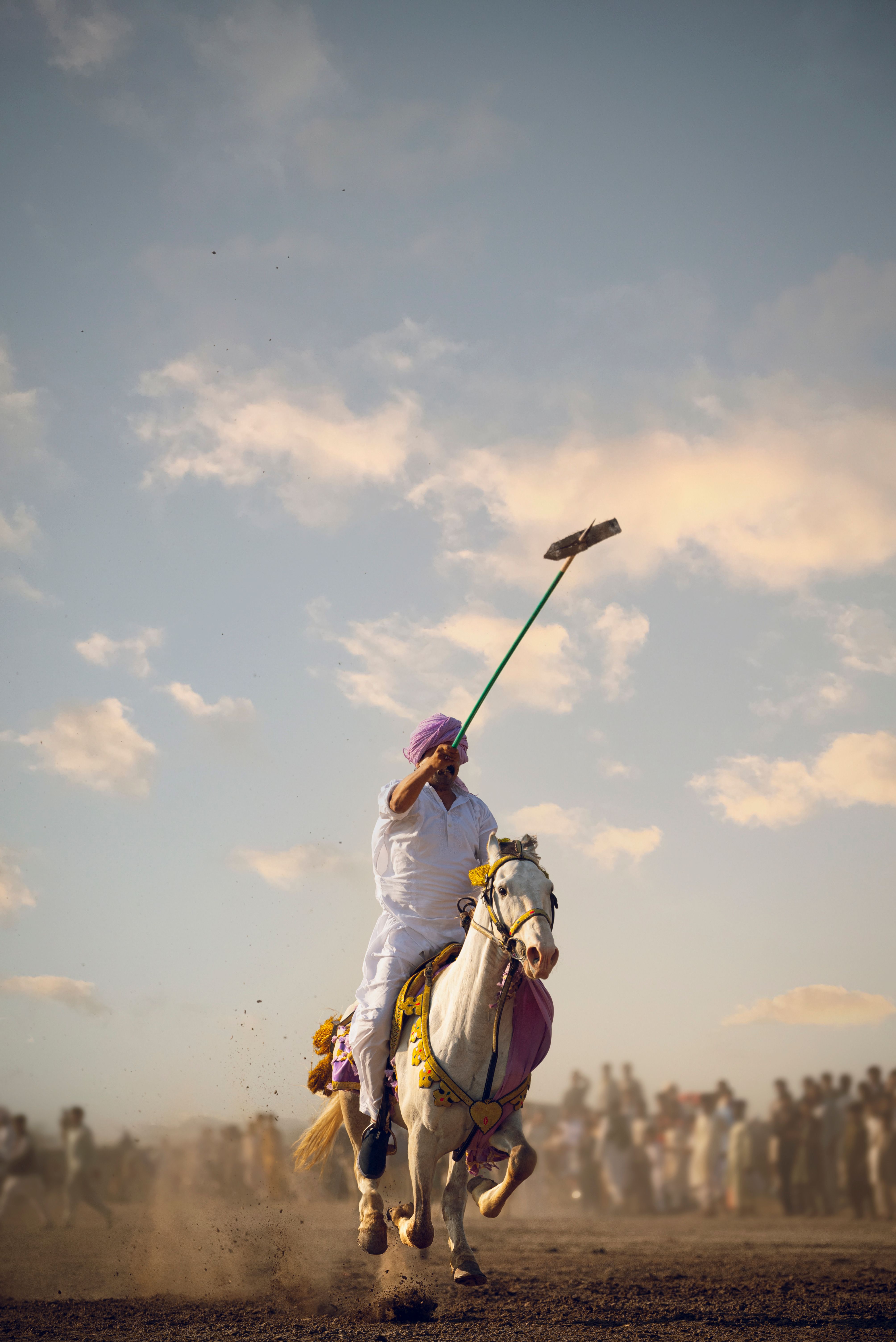 A rider performs tent pegging on a white horse during a traditional event in Pakistan.