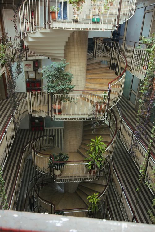 Free Indoor spiral staircase adorned with various hanging and potted plants. Stock Photo
