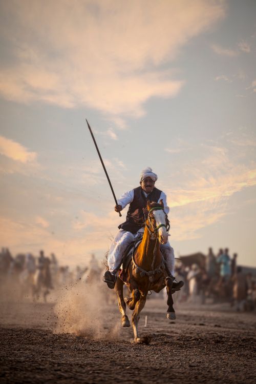 Free A rider in traditional attire gallops on horseback at sunset, showcasing cultural heritage. Stock Photo