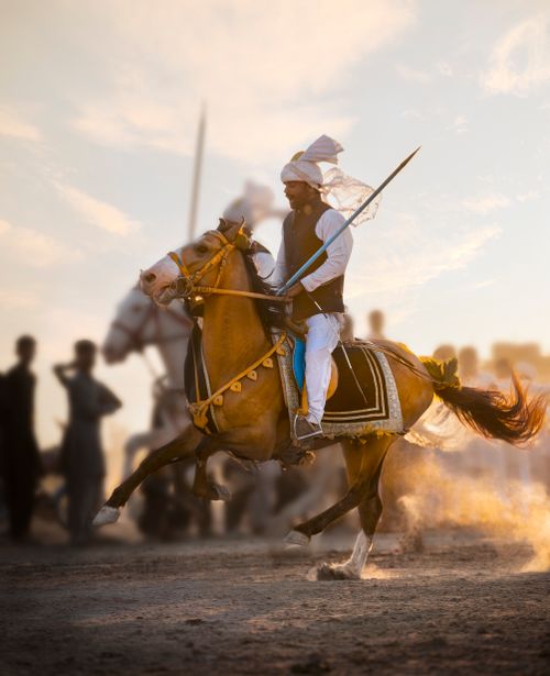 Free A horseman in traditional attire performs in a vibrant desert festival setting. Stock Photo