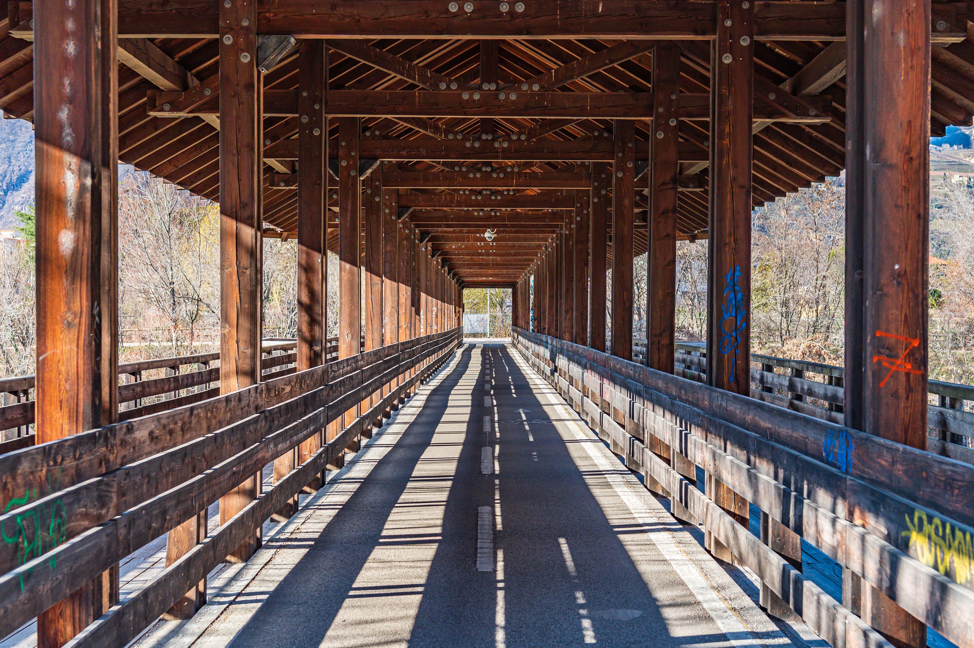 A picturesque view of a wooden covered bridge with graffiti in rural Rome, Italy.
