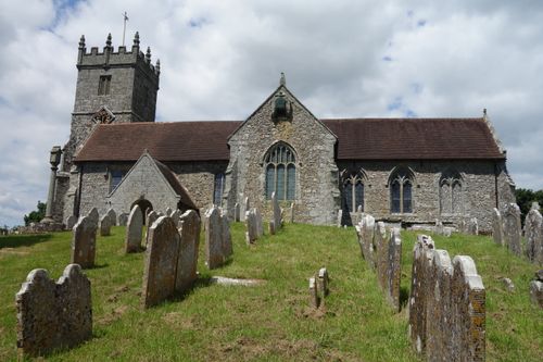 Free A historic stone church with a graveyard in rural England, under a bright sky. Stock Photo