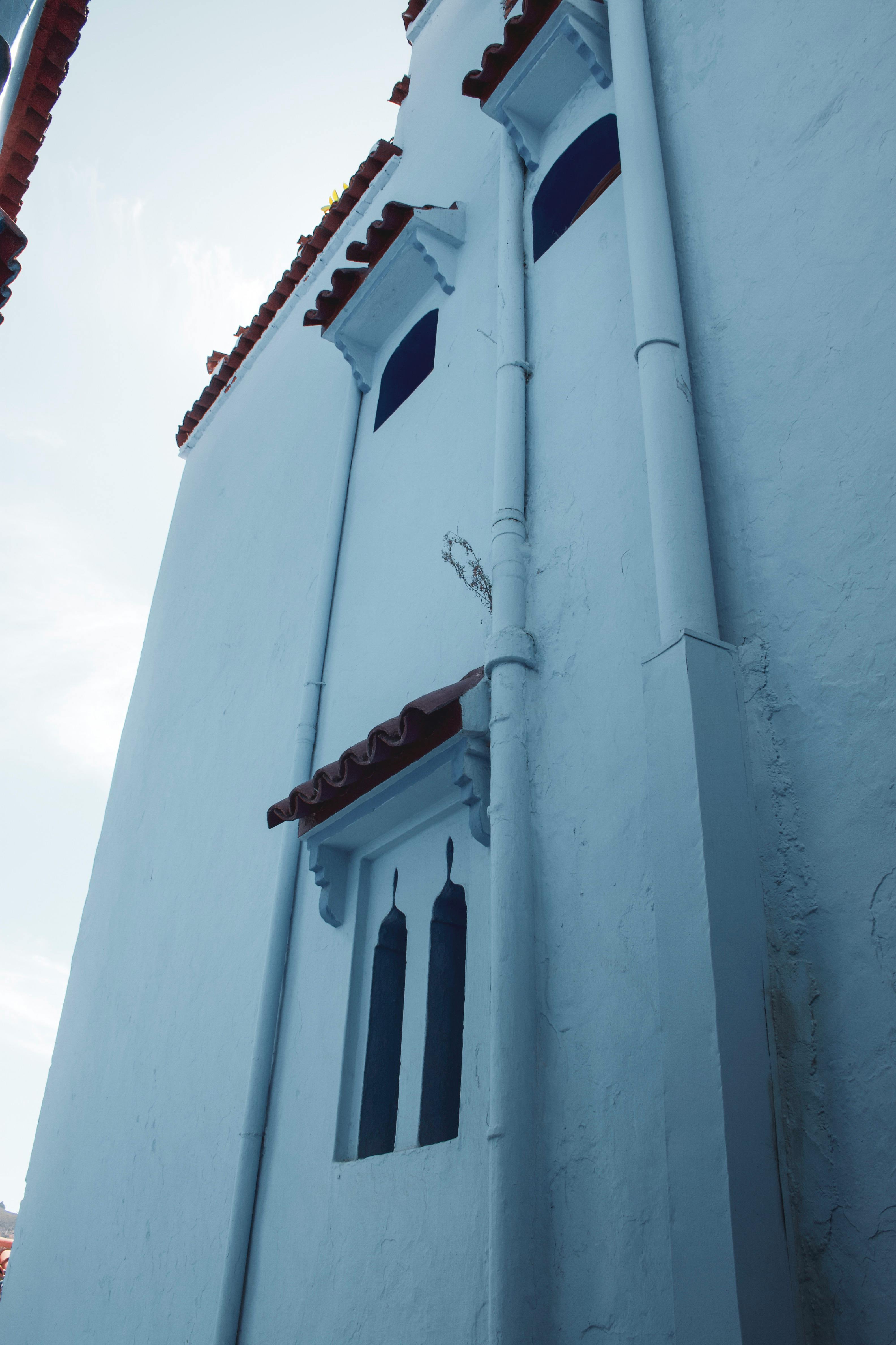 Low-angle view of a traditional blue and white building in Chefchaouen, Morocco.
