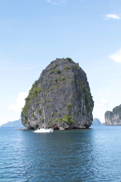 Free Sailboat gliding past towering limestone island in El Nido, Philippines. Stock Photo