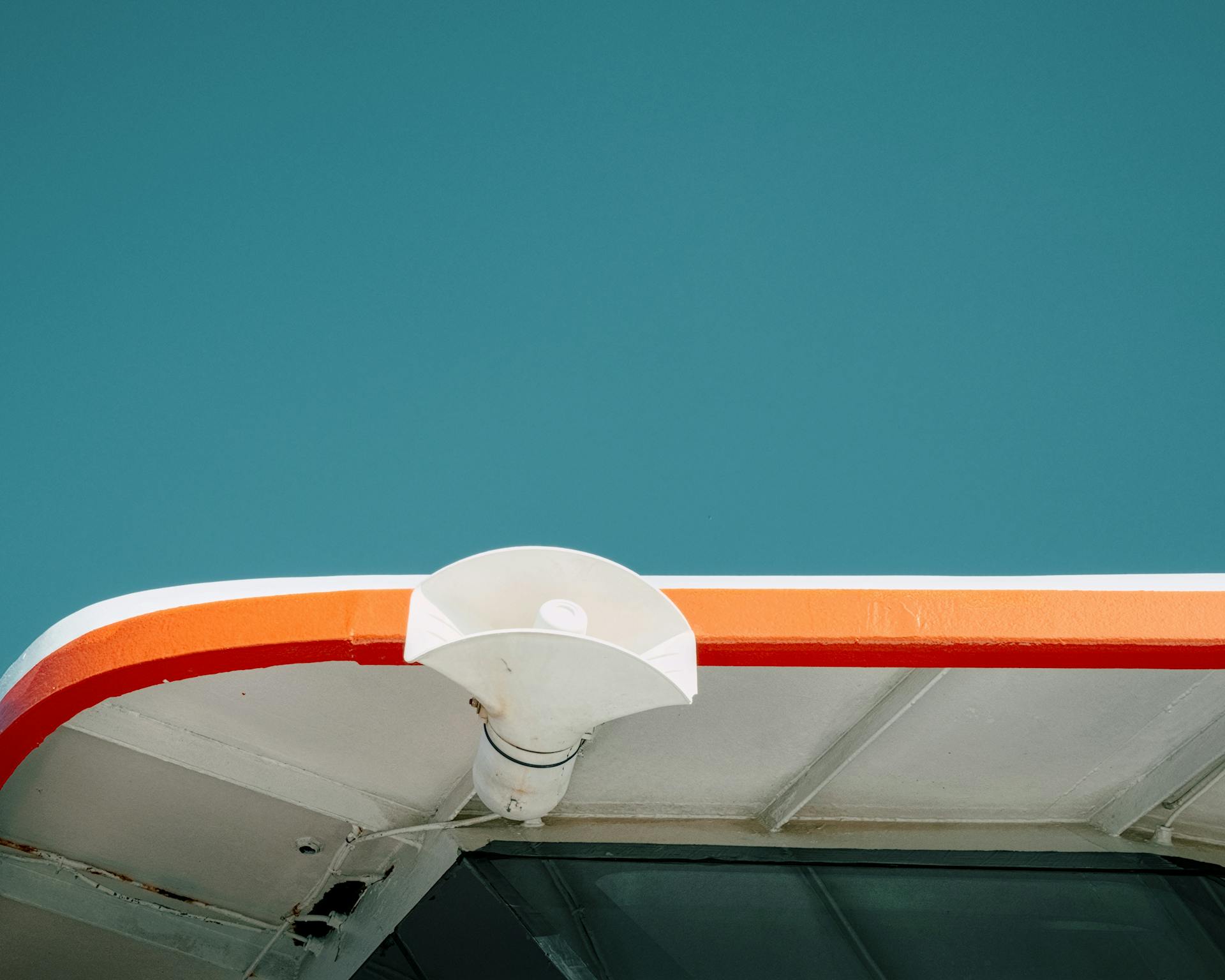 Minimalist photo of a boat roof with colorful trim against a clear blue sky, highlighting modern design.