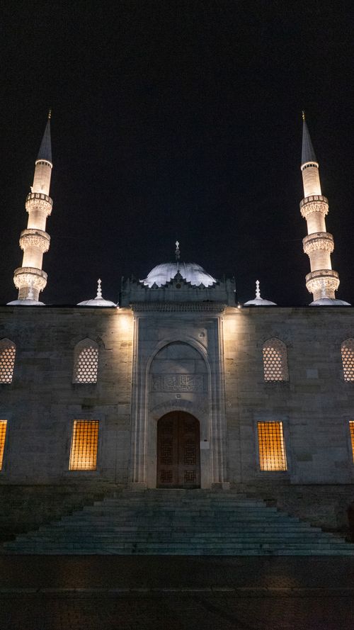 Free A beautifully illuminated mosque at night with two prominent minarets and entrance. Stock Photo