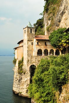 在意大利斯特雷萨马焦雷湖宁静的湖水旁，一座风景如画的修道院坐落在悬崖上