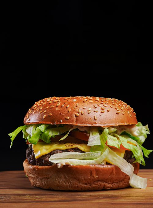 Free Delicious cheeseburger with lettuce, tomato, and cheese on a sesame bun. Stock Photo