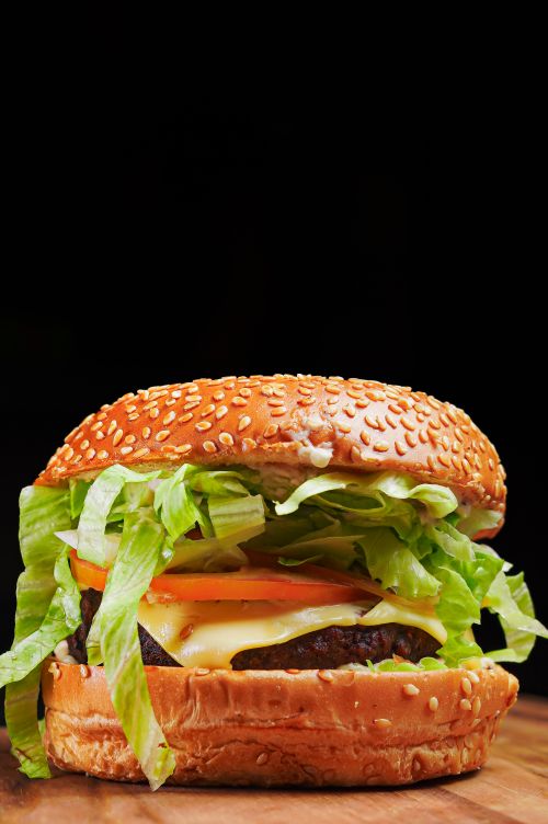 Free Juicy cheeseburger with lettuce, tomato, and melted cheese on a sesame bun. Stock Photo