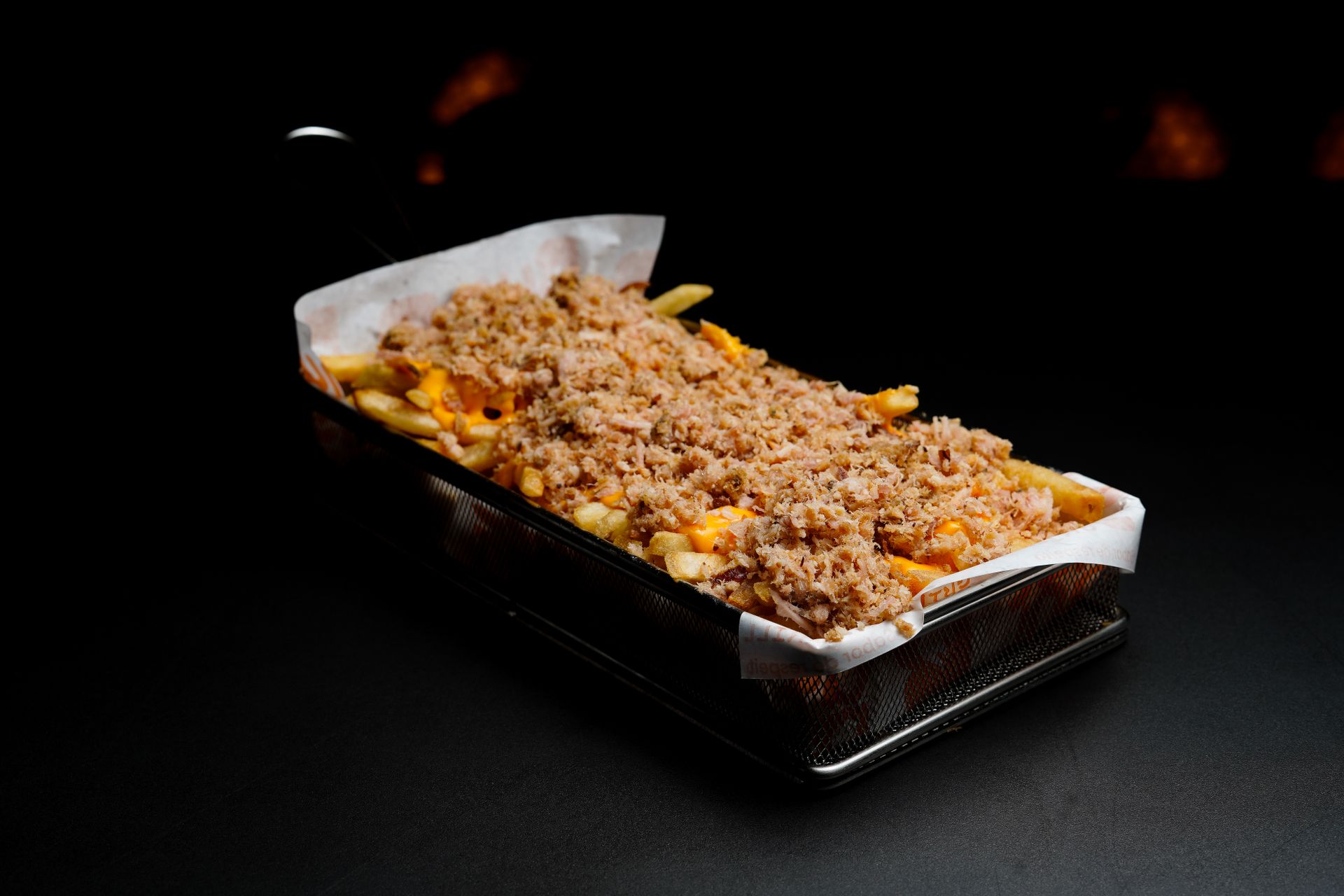 Basket of crispy French fries topped with melted cheese and ground meat, ready to serve.