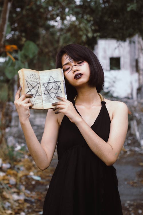 Wanita Mengenakan Gaun Hitam Saat Memegang Buku