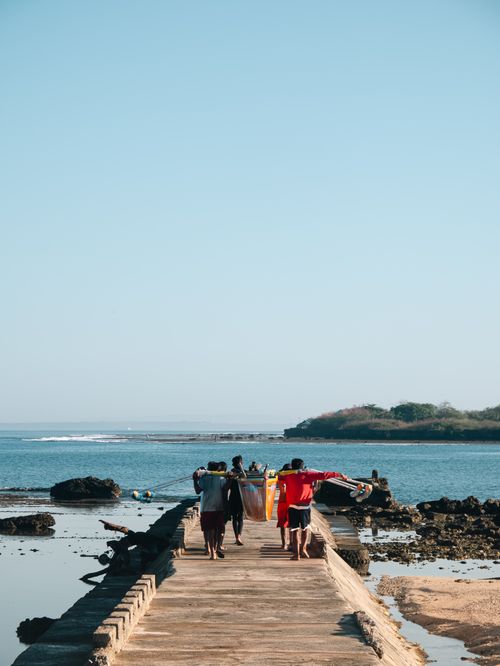 Free A group of fishermen carrying a net on a rustic pier in Badoc, showcasing island life under blue skies. Stock Photo