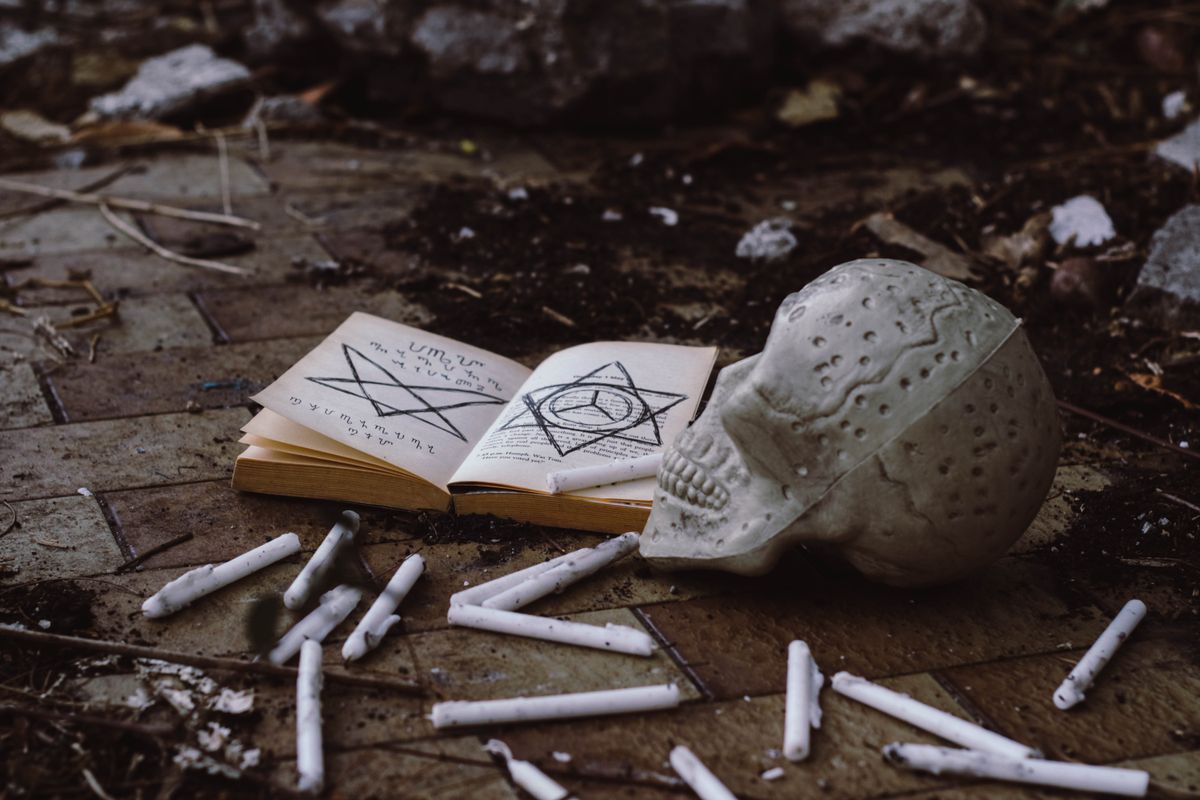 An apothecary of dried roses, glass vials, and aged parchment — the keeper's working table