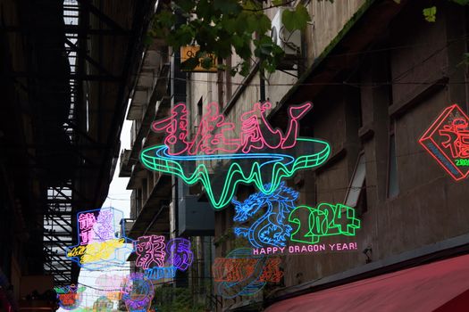 Colorful neon signs celebrating Happy Dragon Year 2024 in a Chongqing alleyway.
