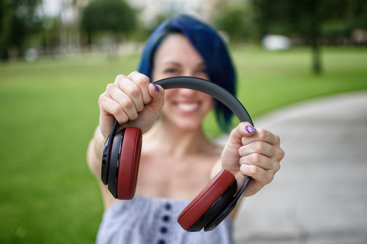 smiling woman with headphones in a grassy park setting