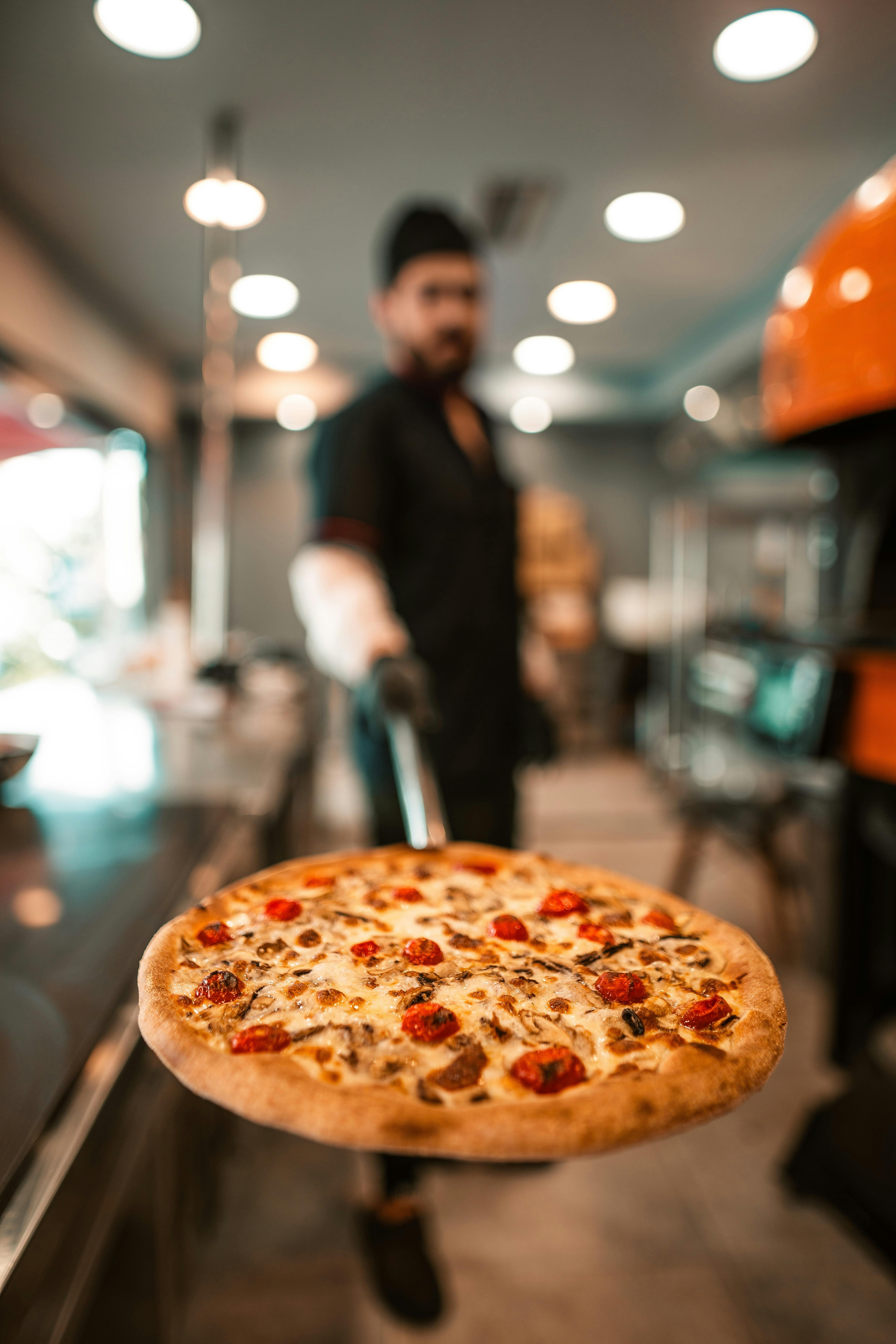 Chef presenting a freshly baked gourmet pizza in a stylish restaurant.