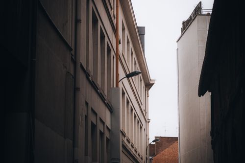Free A narrow alley flanked by modern buildings, capturing urban architecture's minimalist aesthetic. Stock Photo