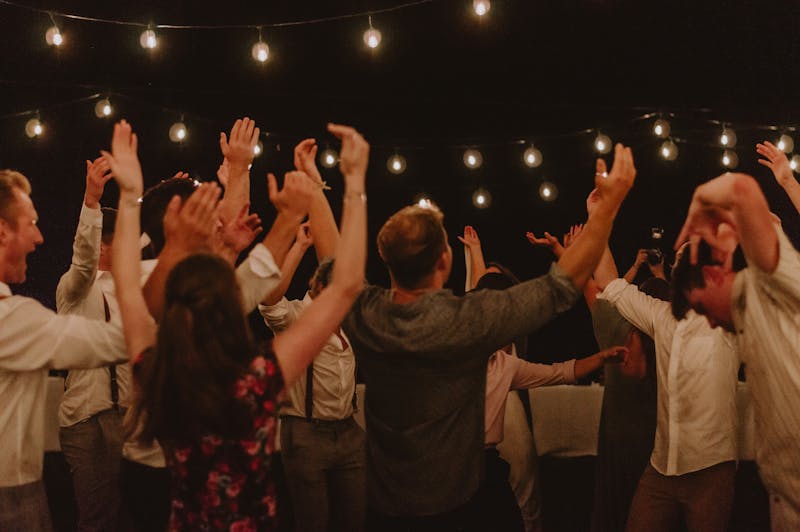 Group of adults dancing under string lights at an outdoor party