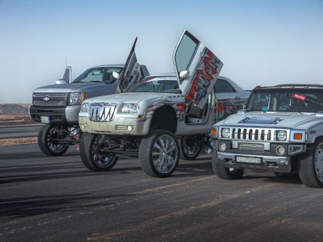 Modified cars including a Chrysler C300 and Hummer H1 in Riyadh desert, showcasing customization and desert aesthetics.