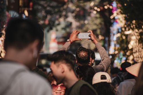 Free A lively street festival in Hanoi, Vietnam with people capturing moments on smartphones. Stock Photo