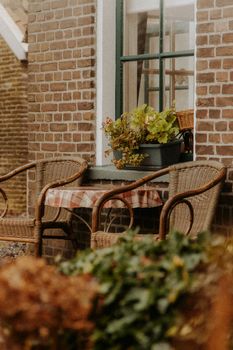 A quaint outdoor patio setup featuring wicker chairs and table in a rustic village setting.