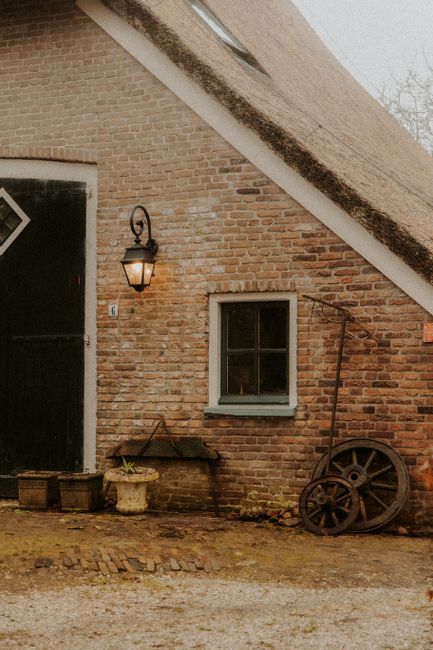 Quaint rustic cottage wall with old wagon wheel and window, reflecting vintage charm.