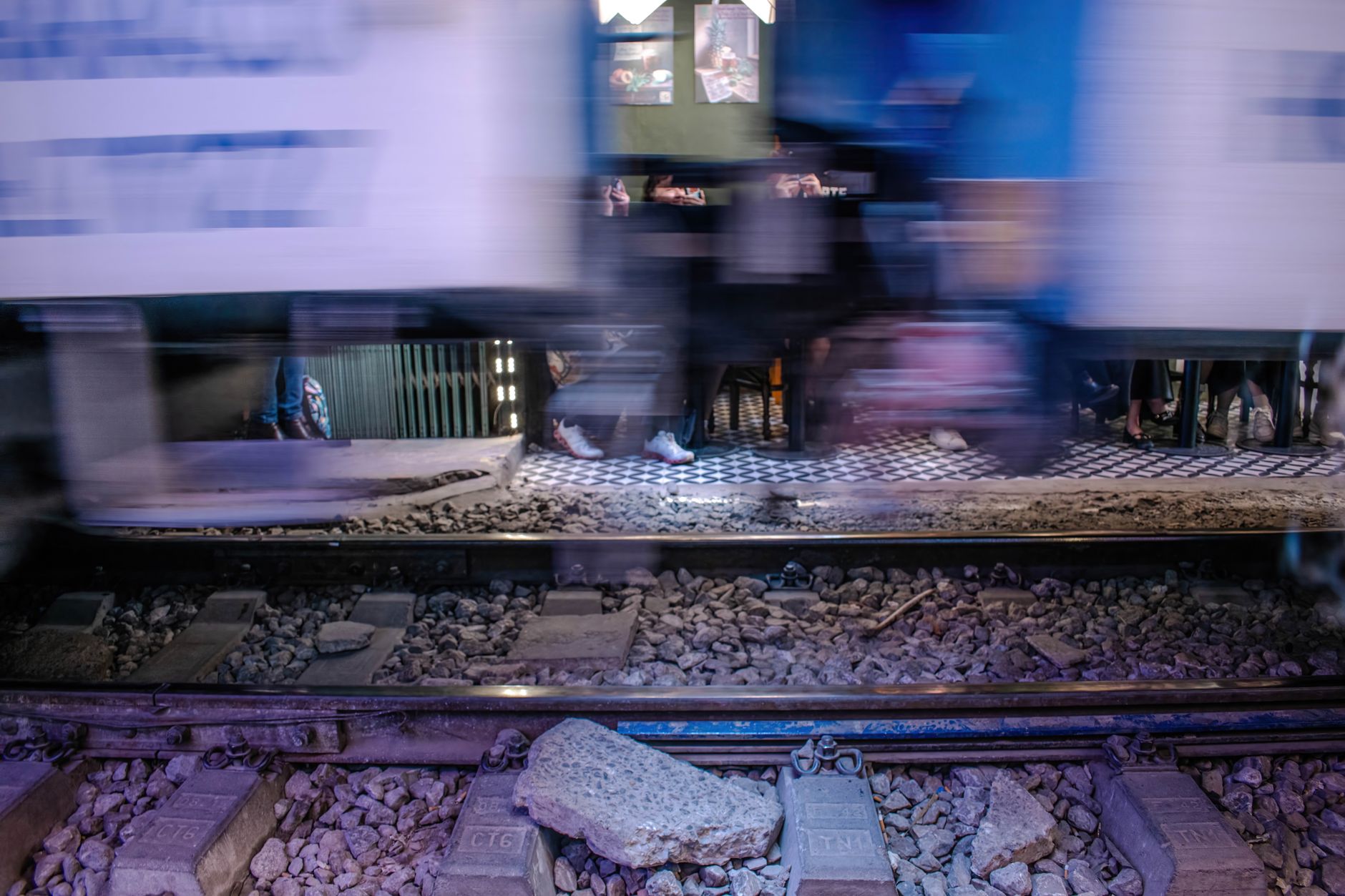 Blurred image of a train passing by a pedestrian area in Hanoi, Vietnam at night.