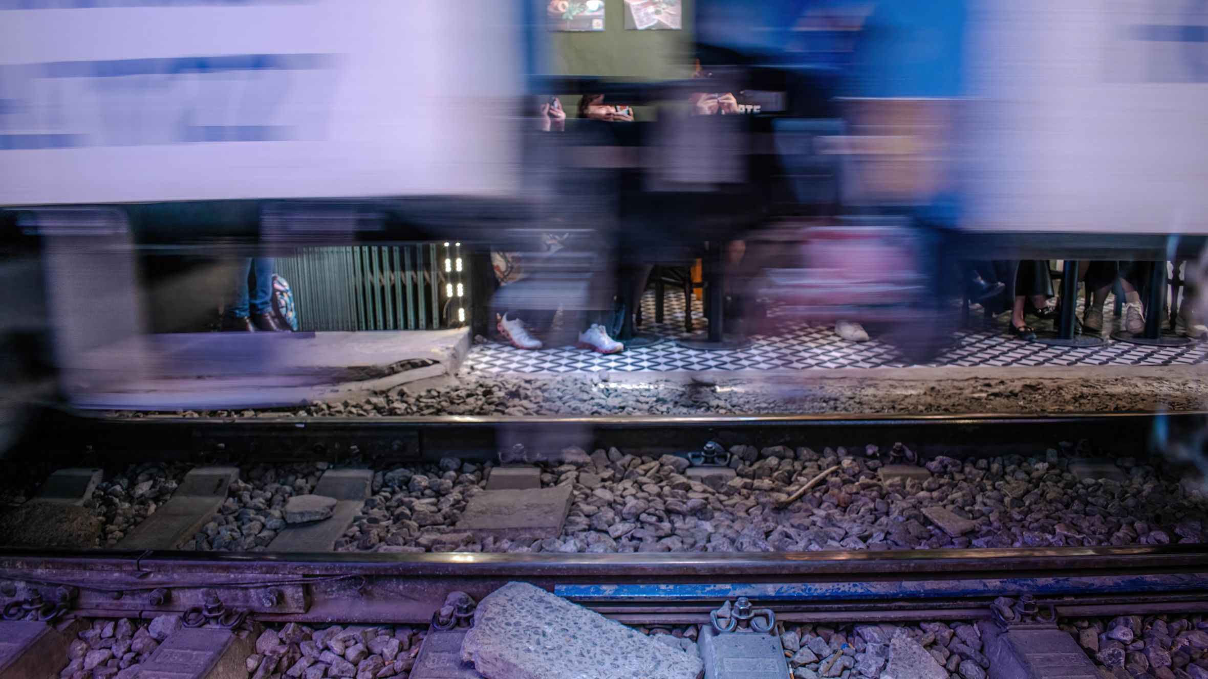 Blurred image of a train passing by a pedestrian area in Hanoi, Vietnam at night.