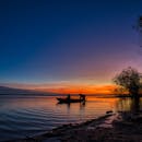 日落时分，两人在湖中平静地划船，在充满活力的暮色中形成一幅如画的剪影