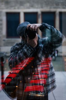 A photographer captures their own reflection in a city window.