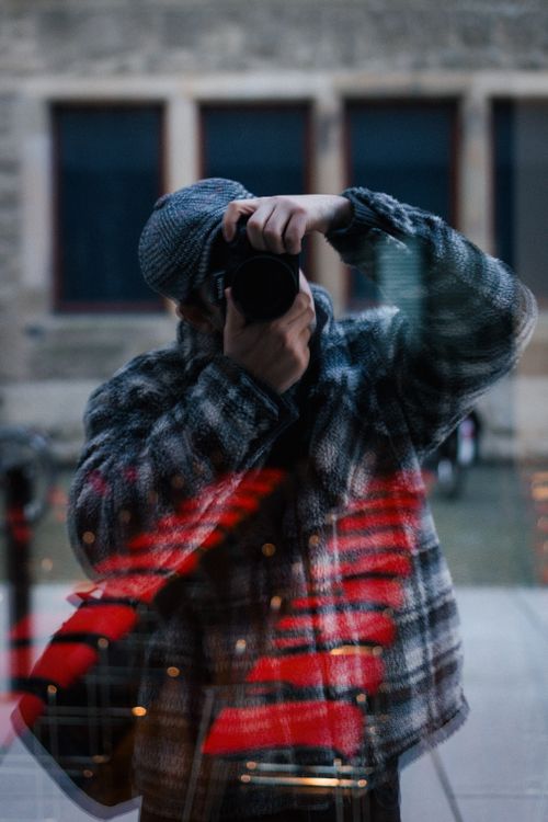 Free A photographer captures their own reflection in a city window. Stock Photo