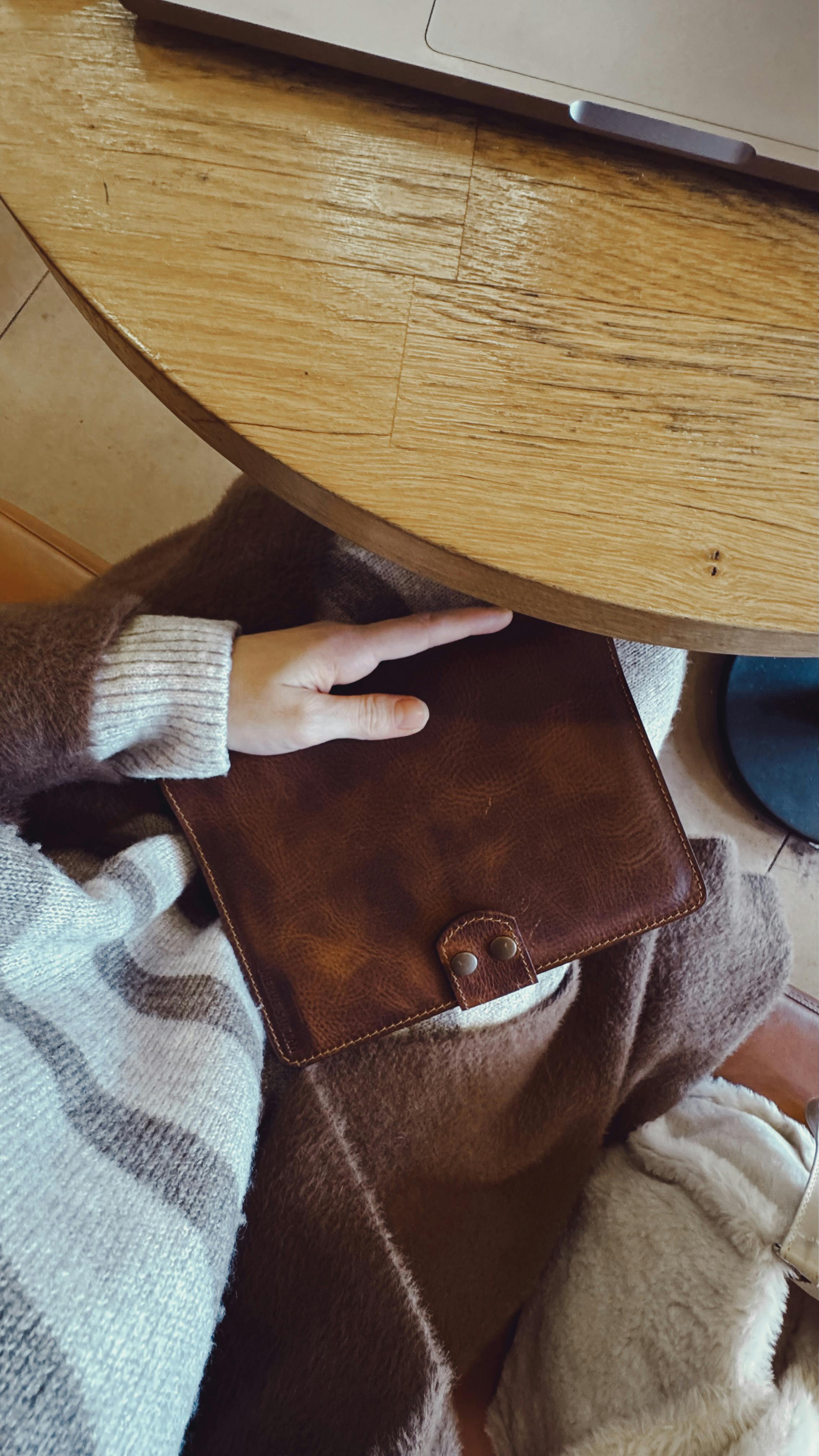 Gratuit O persoană într-un cadru confortabil ținând un notebook din piele lângă un laptop pe o masă de lemn. Fotografie de stoc