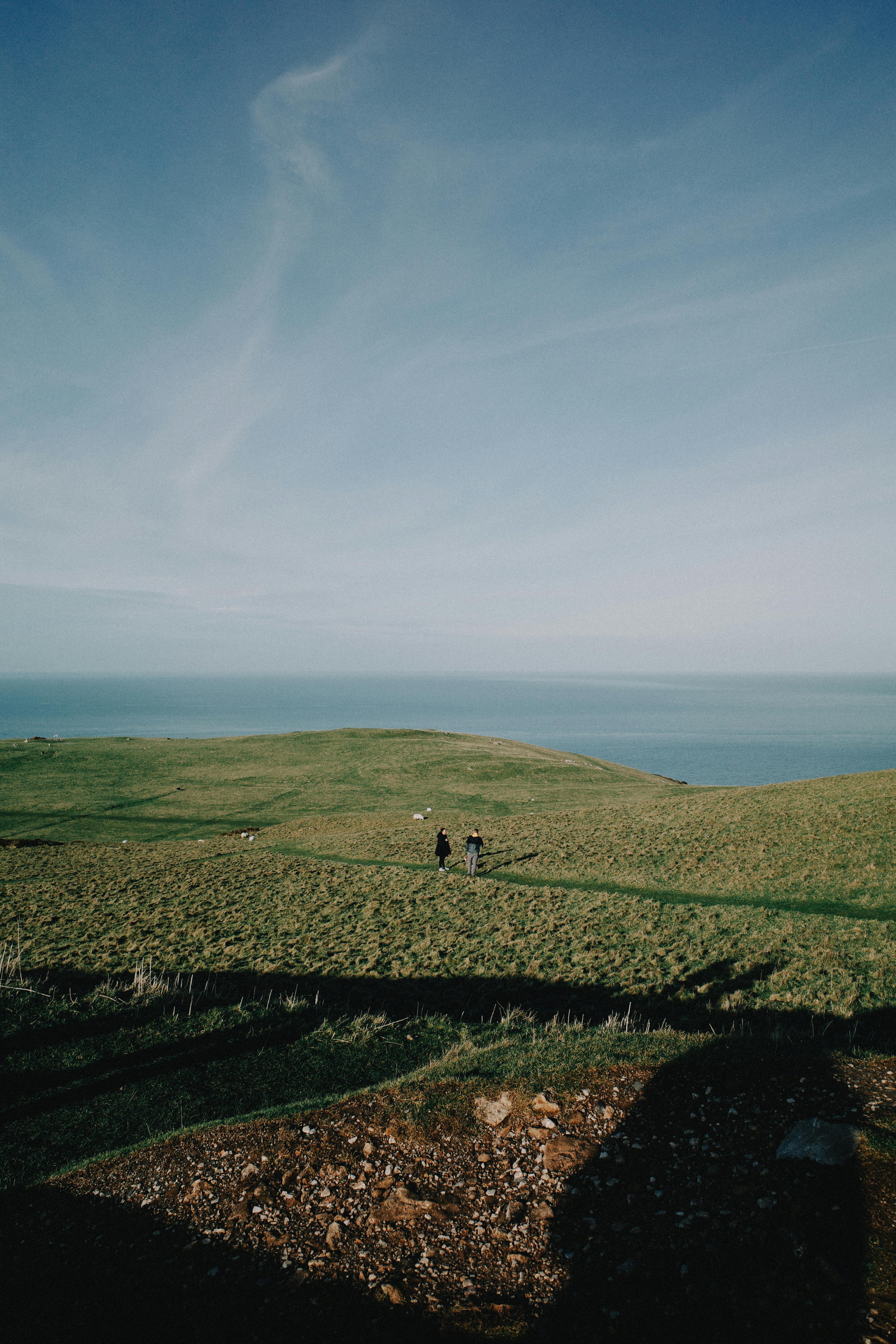 Two people walking on Welsh coastal cliffs with ocean view.