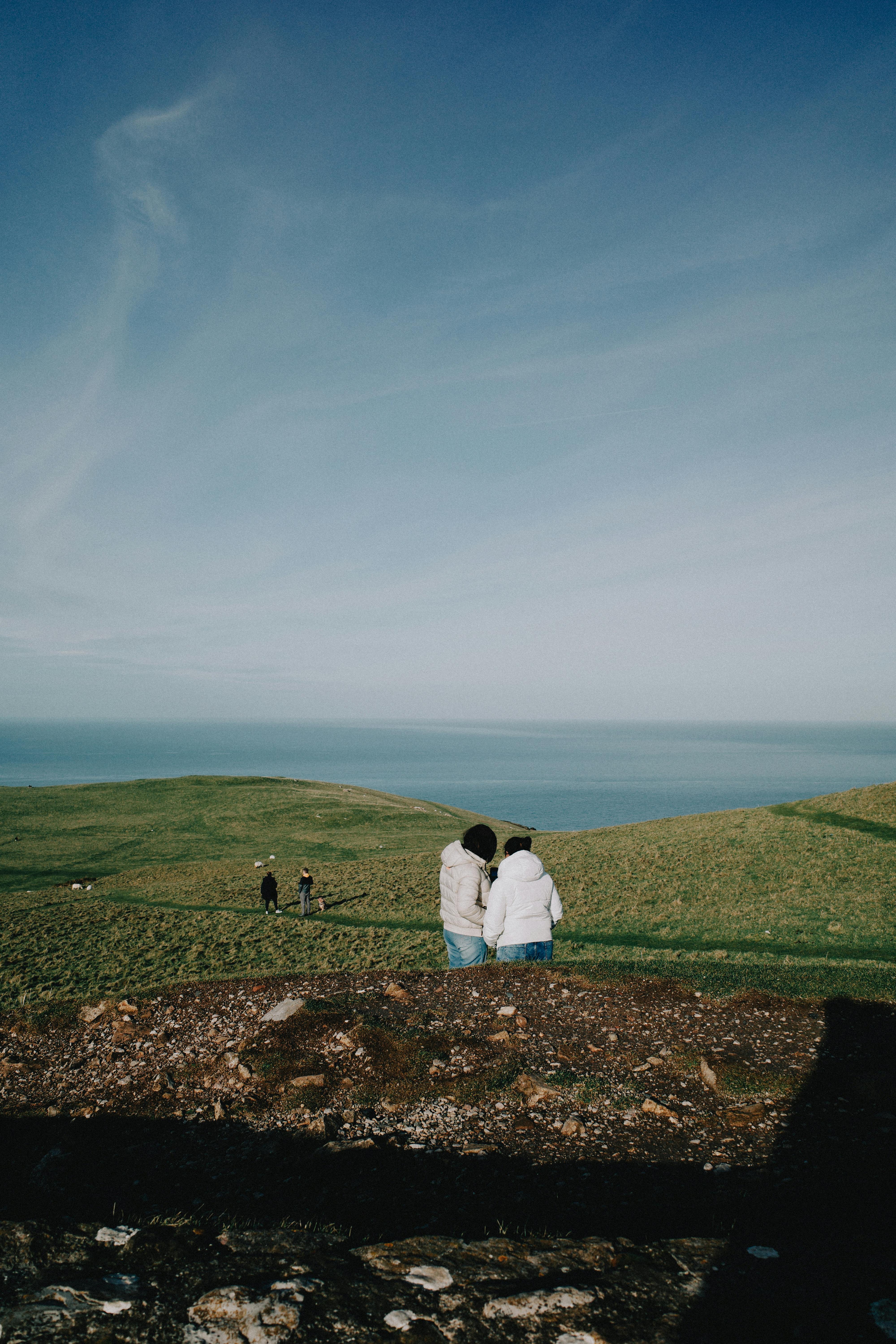 People enjoying a picturesque walk on Welsh cliffs overlooking the ocean.