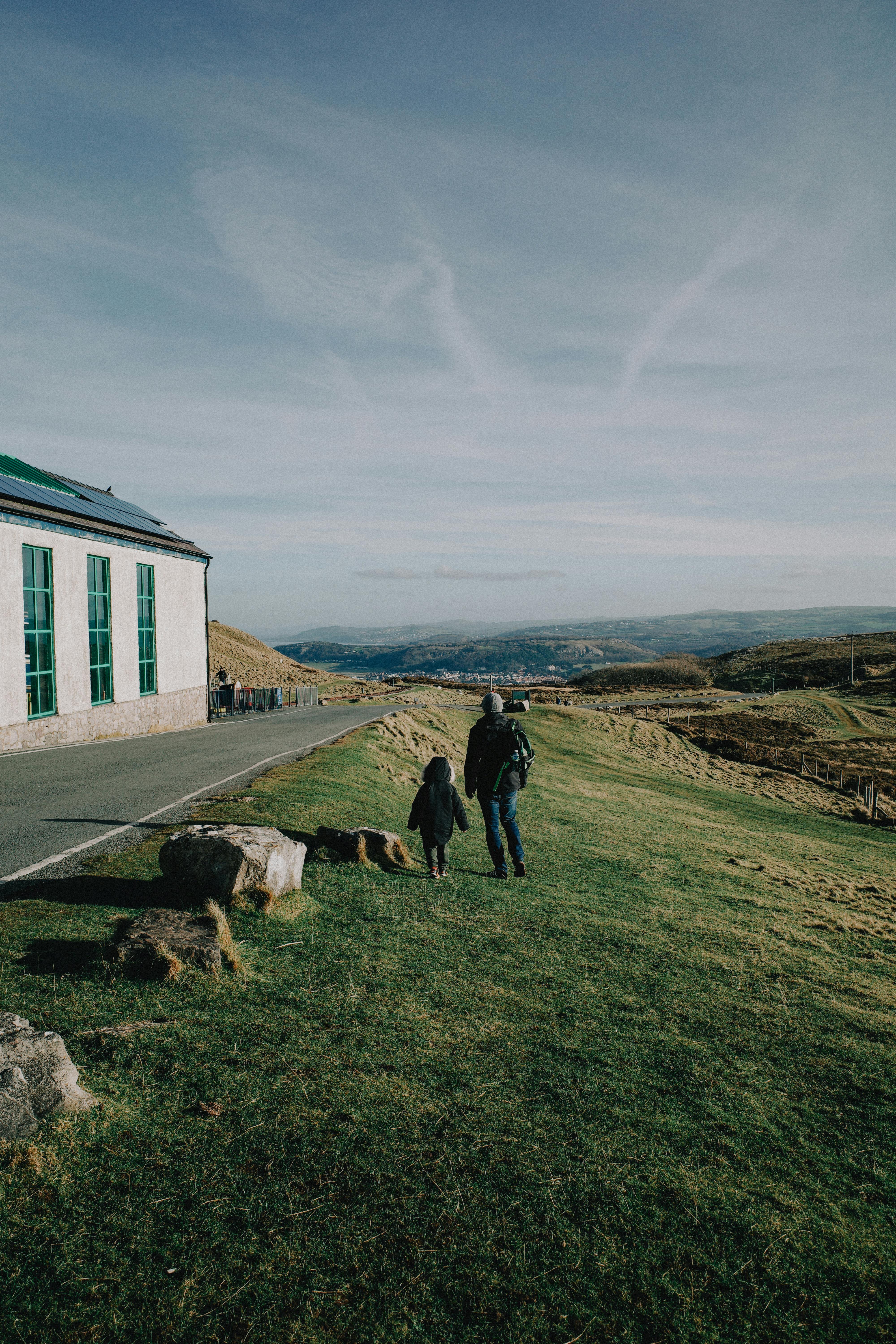 A father and child walk along a hillside in North Wales, capturing serene nature views.