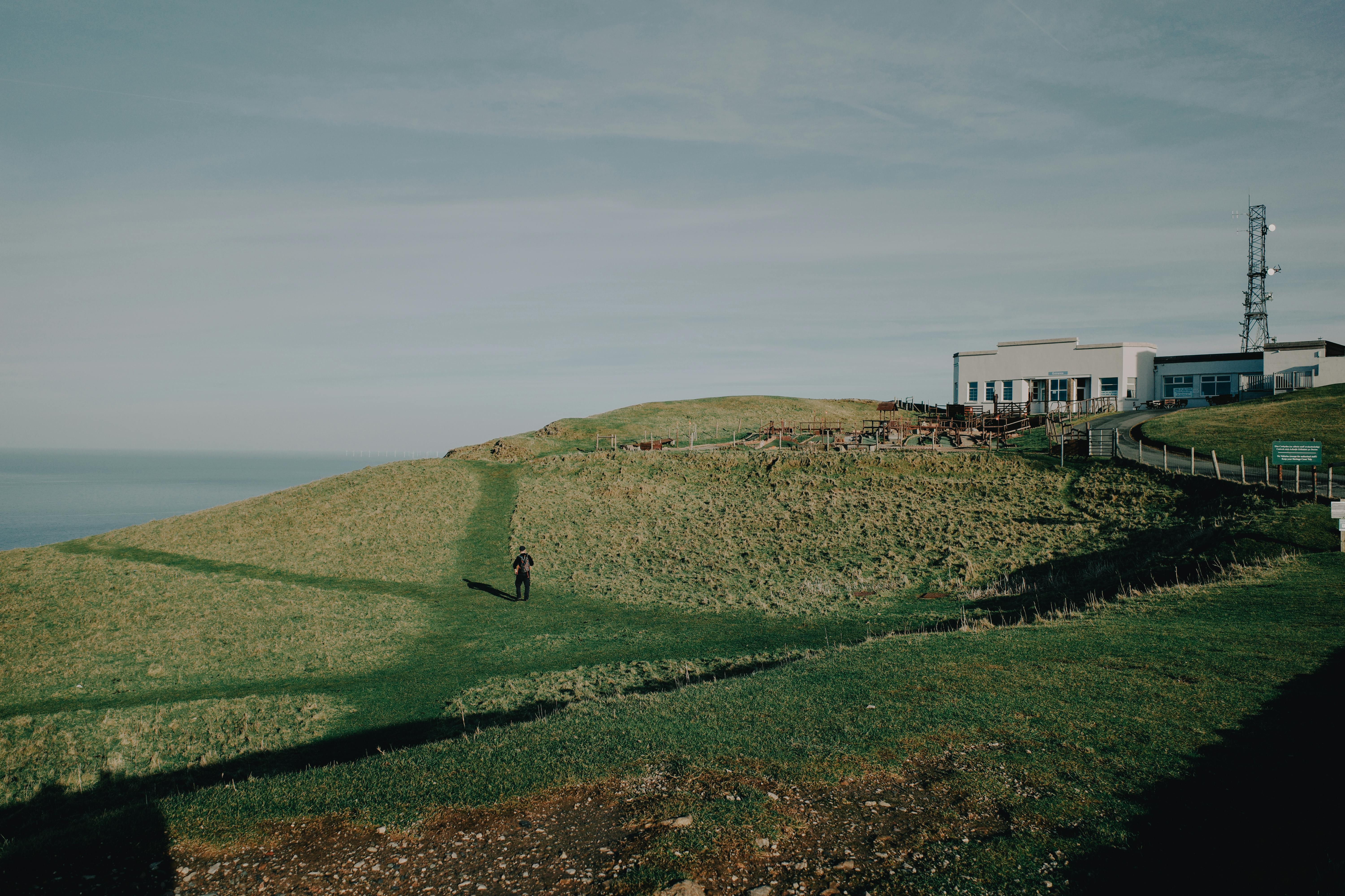 Scenic hilltop with a lone figure and a coastal building in Llandudno, North Wales.