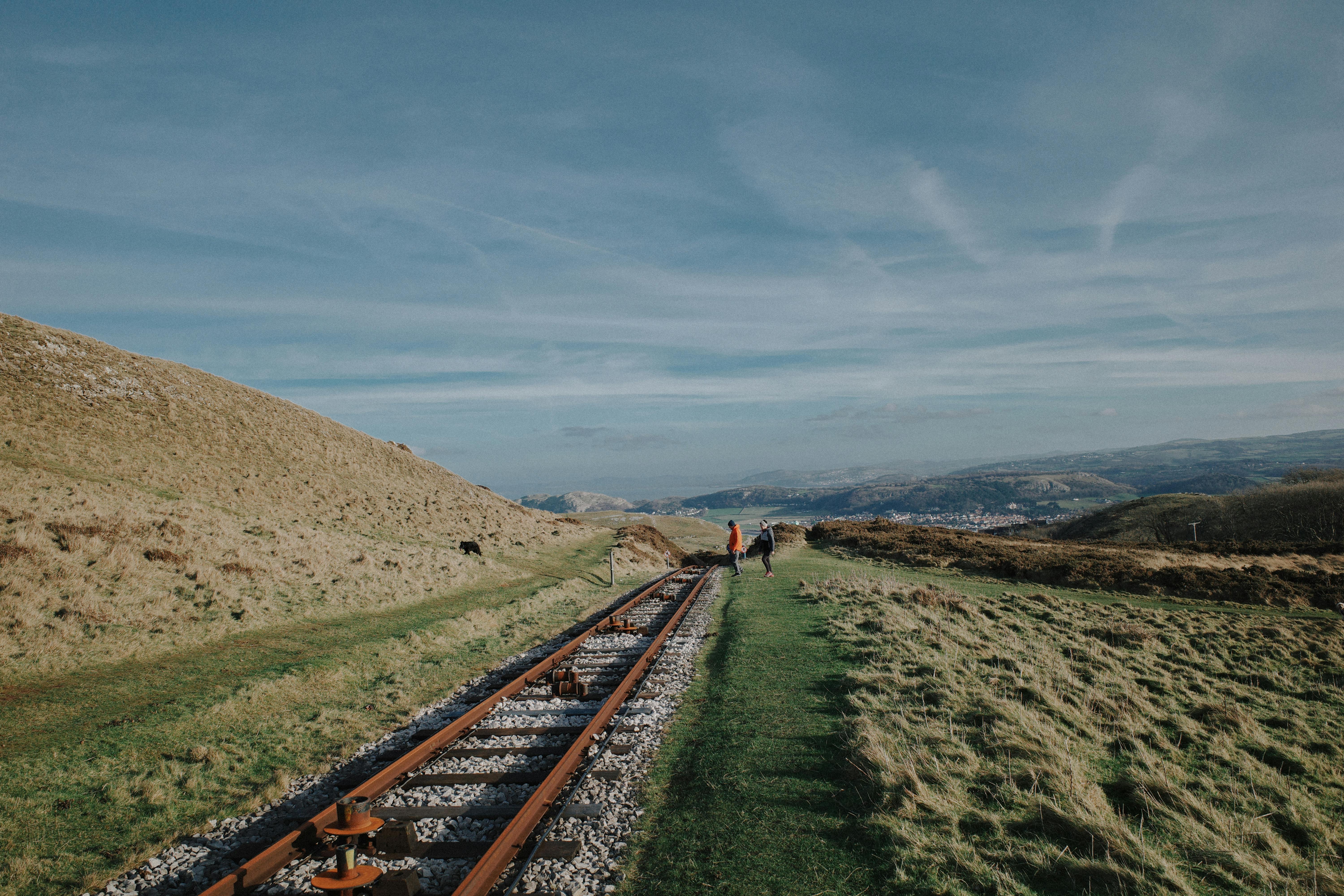 Explore the lush Welsh countryside with this captivating image of railway tracks leading through rolling hills under a vast sky.