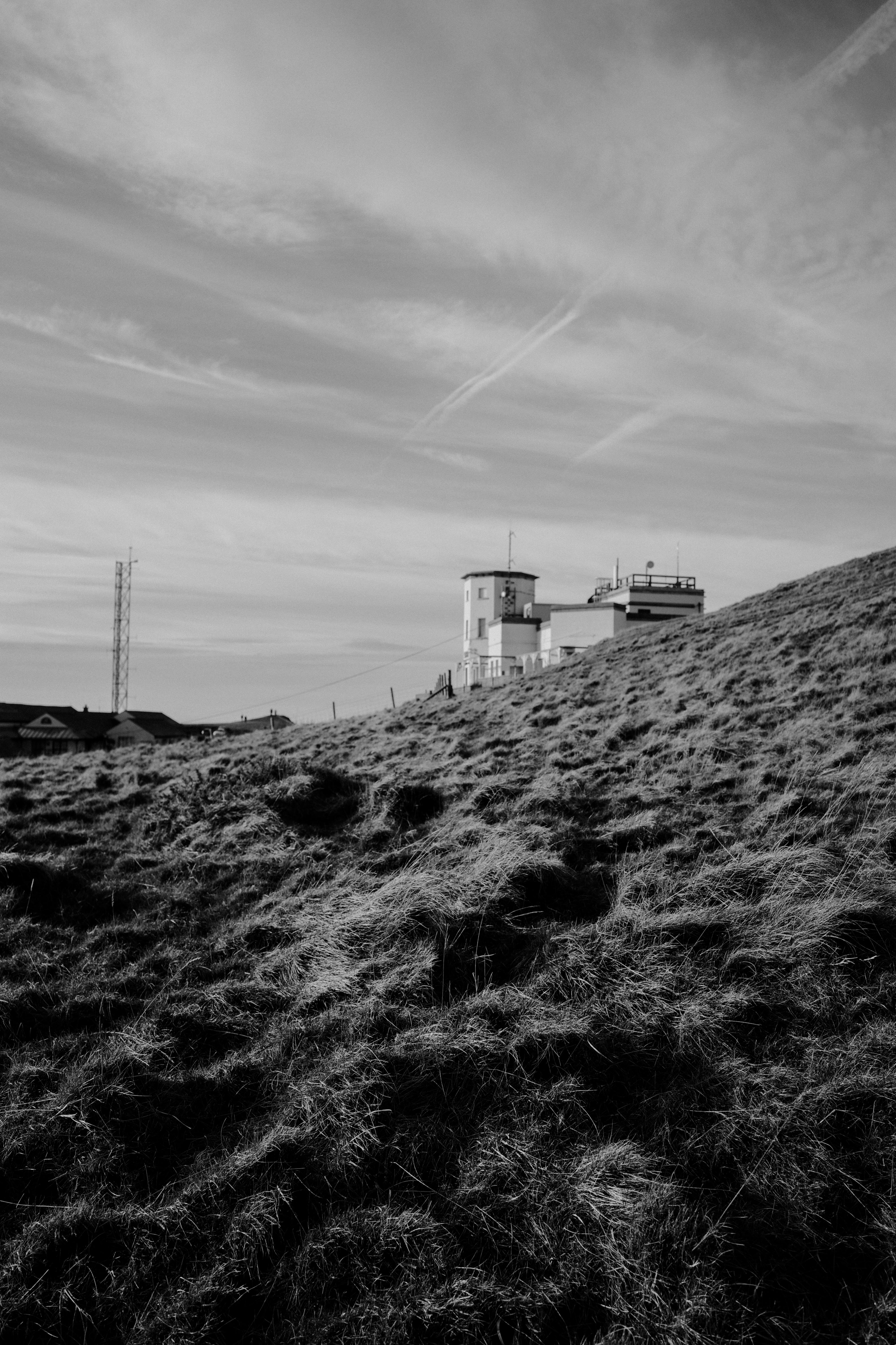 Black and white photo of a modern building atop a grassy hill in Wales.