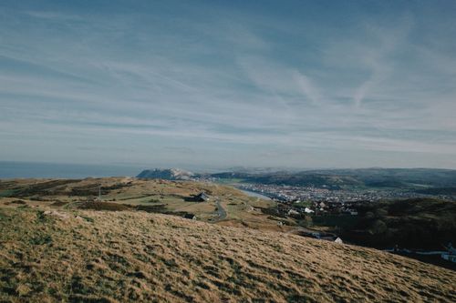 Free Panoramic view of the coastal countryside in Wales, capturing lush green landscapes and distant hills. Stock Photo