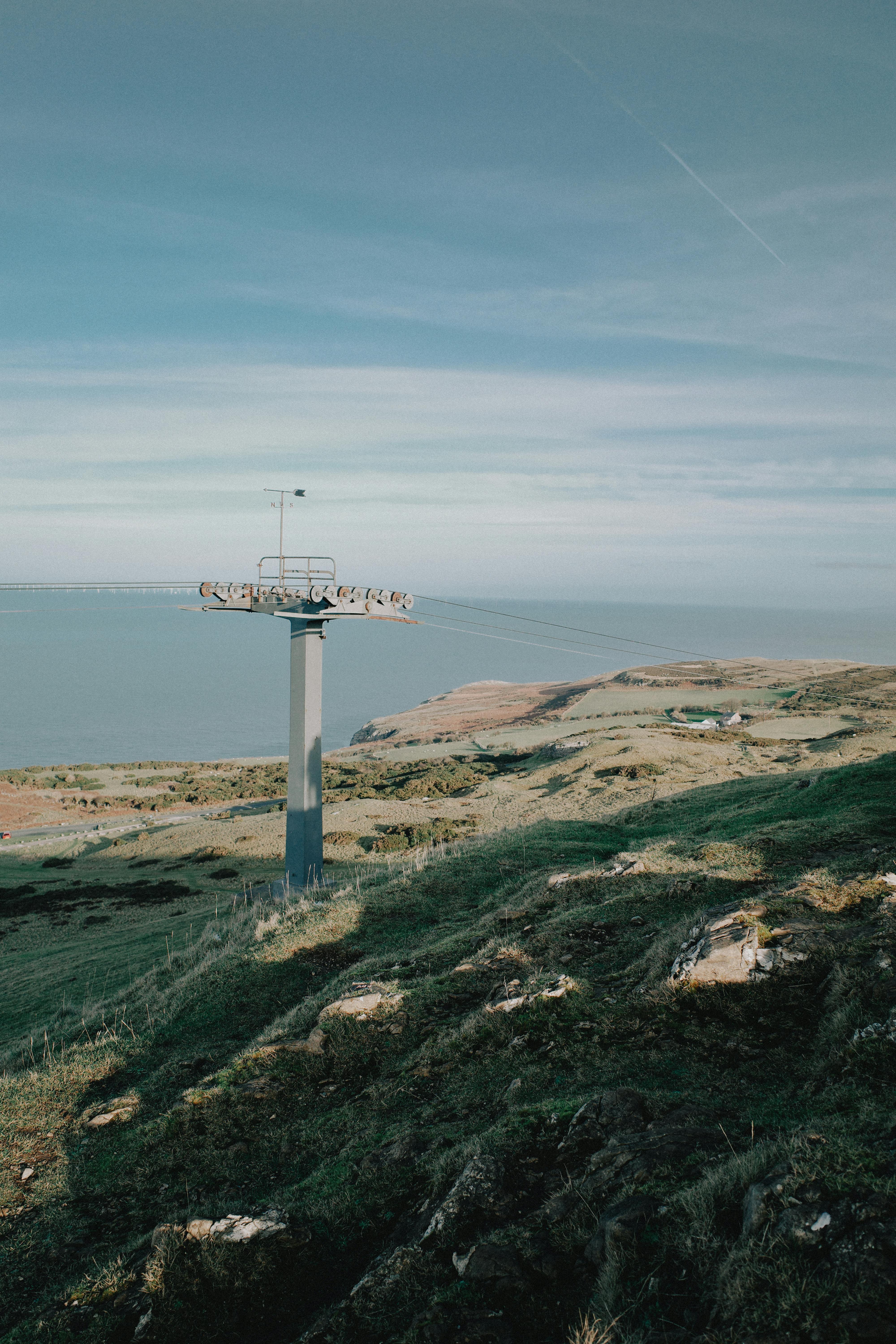 A picturesque landscape in Wales, featuring rolling hills and a cable car post.