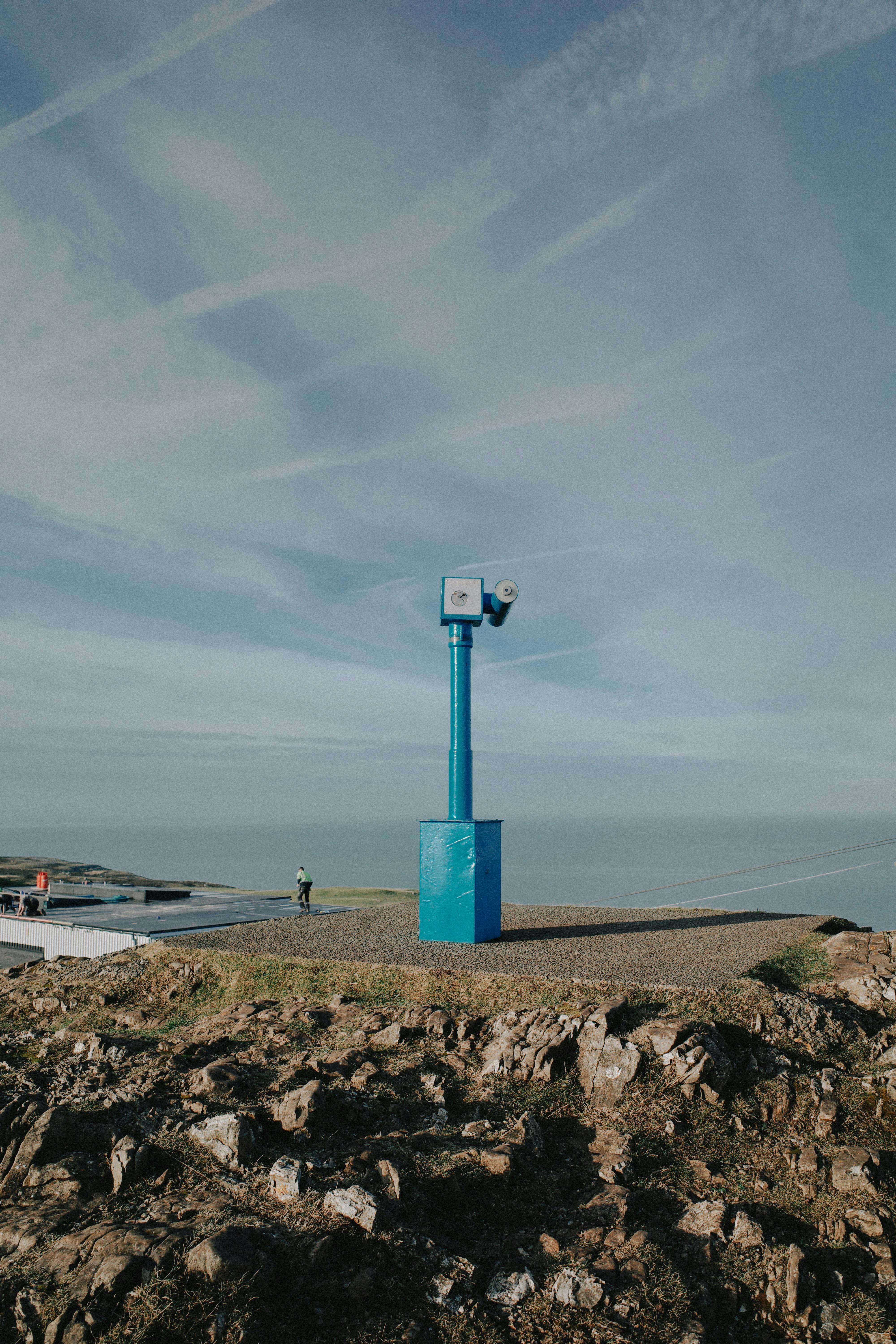 A blue telescope atop a rocky hill offers stunning views of the Welsh coastline.