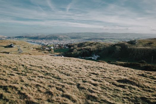 Une vue imprenable sur les collines et une ville pittoresque du Pays de Galles sous un ciel clair.