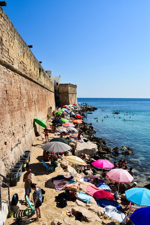Gratis Persone che si godono una giornata di sole su una spiaggia rocciosa in riva al mare a Gallipoli, in Italia. Foto a disposizione