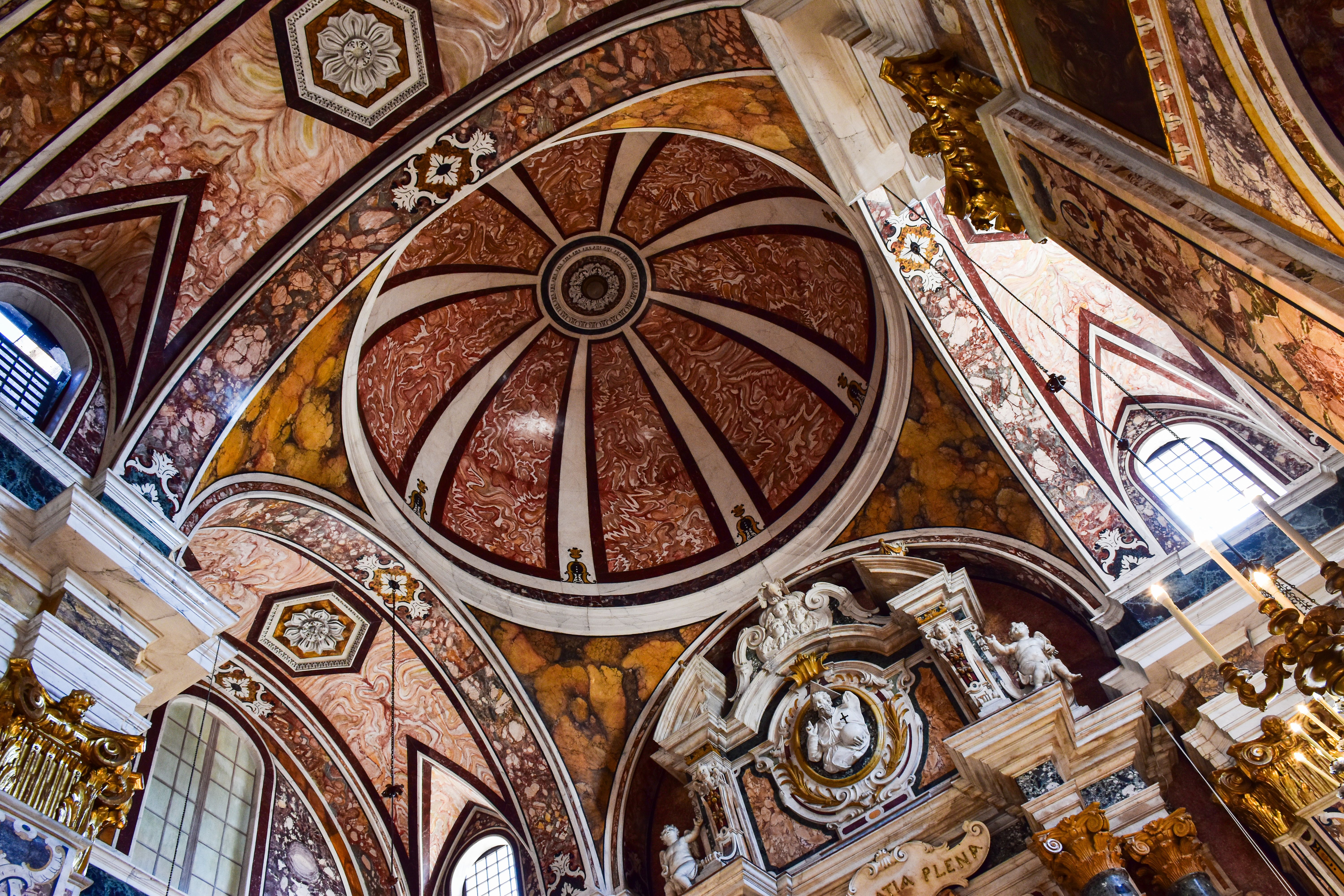 Ornate baroque interior of St. John's Co-Cathedral in Valletta, Malta, showcasing intricate gold leaf and frescoes.