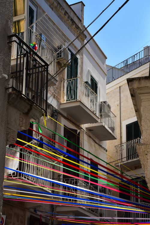 Free Vibrant ribbons decorate balconies in Apulia, Italy, evoking a festive mood. Stock Photo