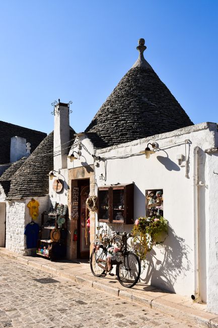 Trulli houses in Alberobello, Puglia, Italy under clear blue sky, showcasing traditional architecture.