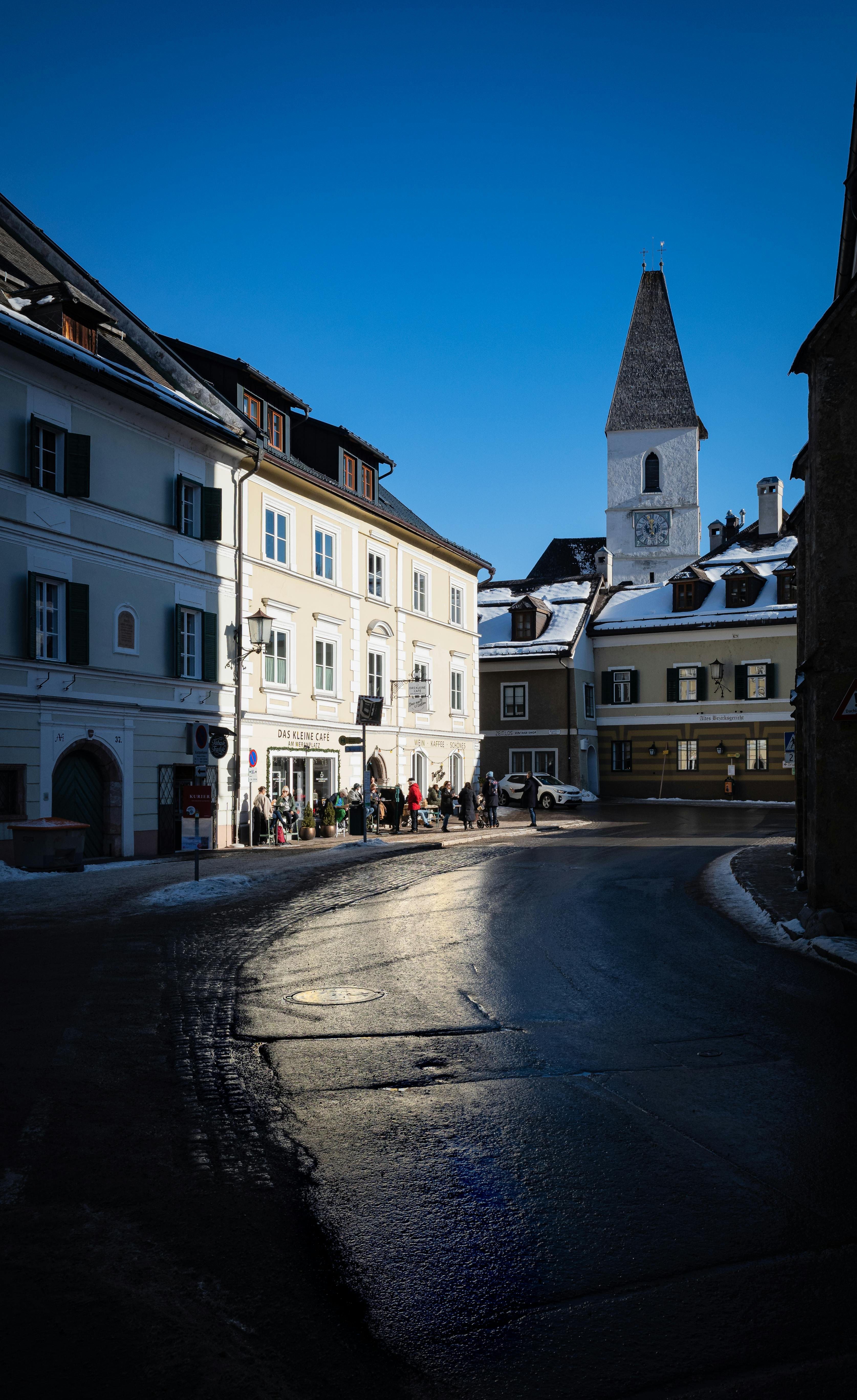 Charming winter scene in historic Austrian town with church and colorful buildings.
