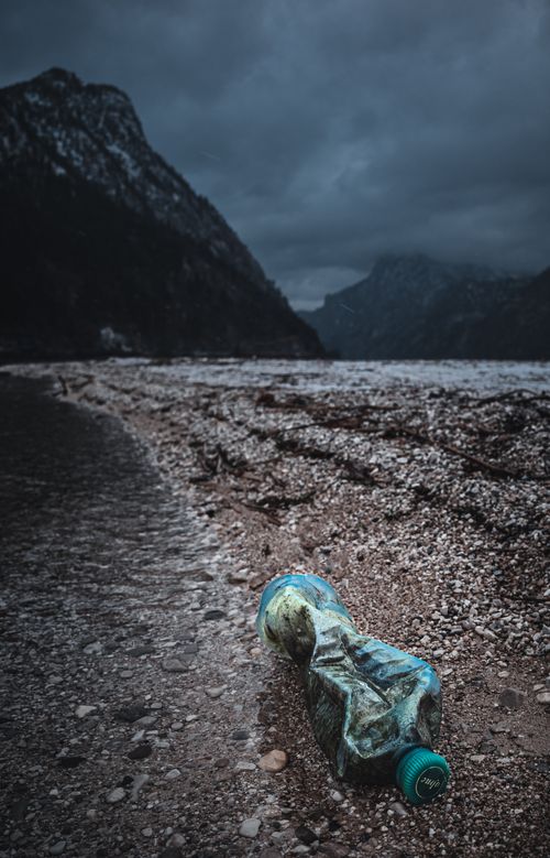Free Plastic waste on a rocky shore by Traunsee Lake under dark skies. Stock Photo