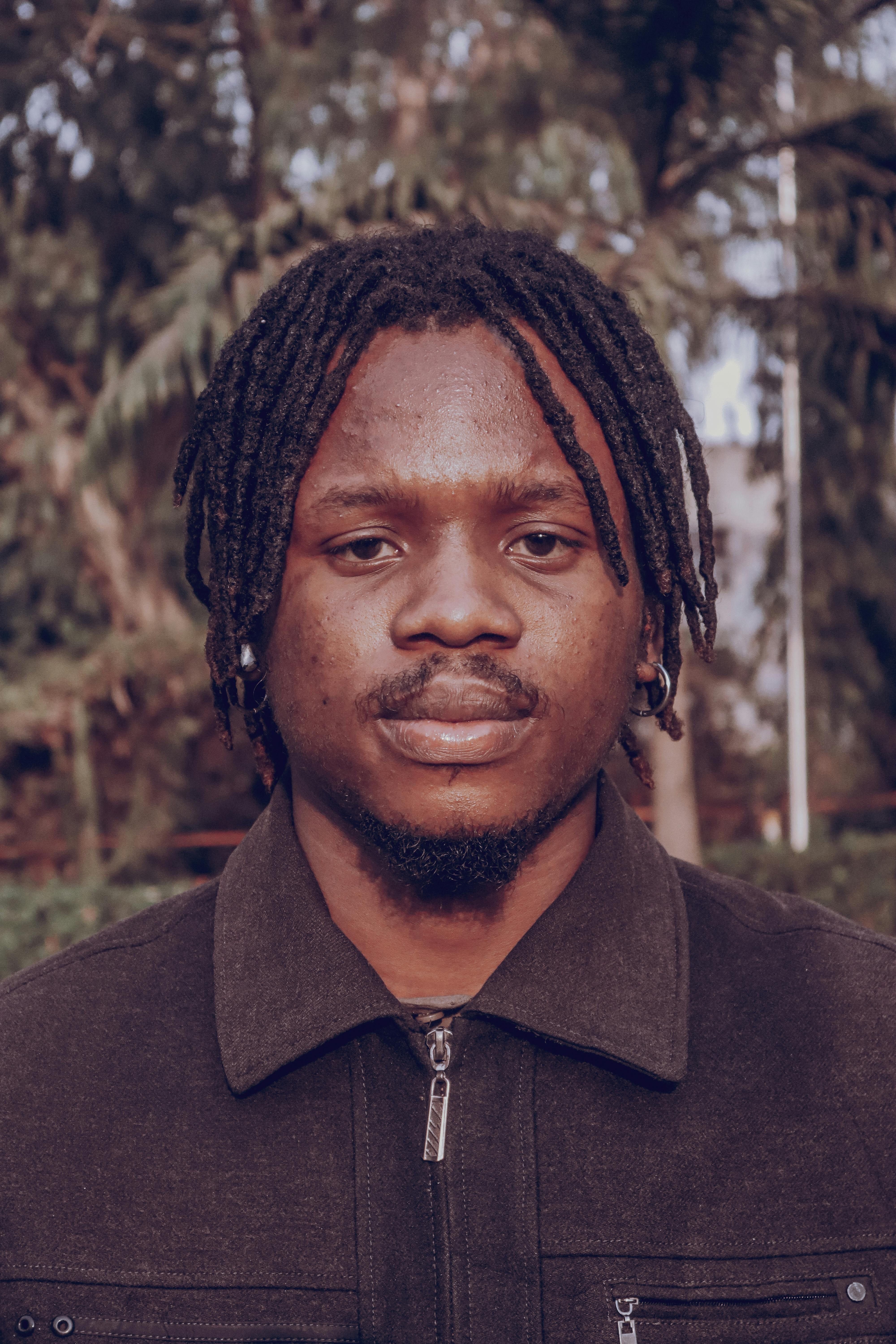 Portrait of a young man with dreadlocks in an outdoor setting, showcasing natural beauty.